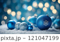 Christmas ornaments resting on snow with blue bokeh lights 121047199