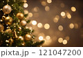 Christmas tree decorated with golden baubles and bells sparkling in the warm light 121047200