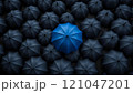 Blue umbrella standing out from the crowd of black umbrellas 121047201