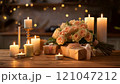 Bouquet of peach roses and gifts on table with burning candles illuminating romantic atmosphere 121047212