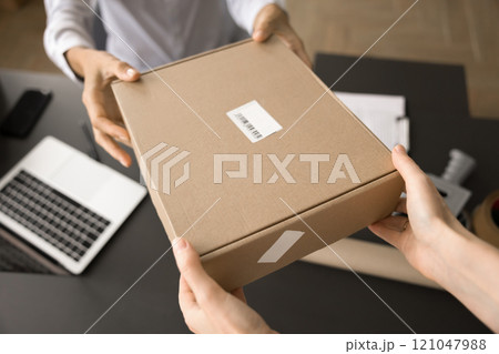 Delivery office employee giving parcel to customer Delivery office employee giving parcel to customer 121047988