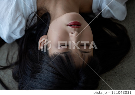 フローリングに寝転ぶ若い女性 121048031