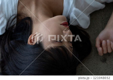フローリングに寝転ぶ若い女性 121048032