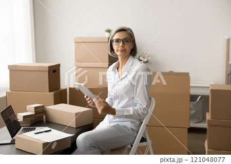 Successful mature business owner woman working in e-commerce storage 121048077