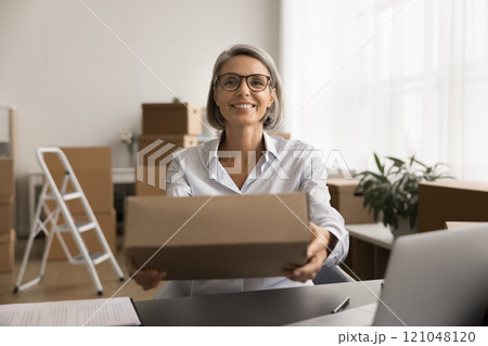 Happy successful businesswoman giving cardboard paper box Happy successful businesswoman giving cardboard paper box 121048120