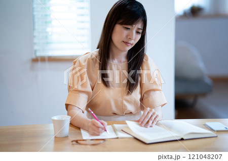 ダイニングテーブルで勉強中に悩むミドル女性 ダイニングテーブルで勉強中に悩むミドル女性 121048207