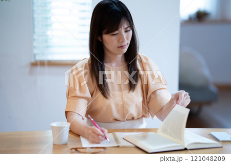 ダイニングテーブルで勉強中に悩むミドル女性 ダイニングテーブルで勉強中に悩むミドル女性 121048209