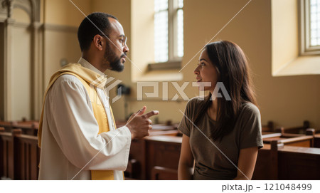 Priest talking to woman in church pews background serious conversation in religious setting 121048499