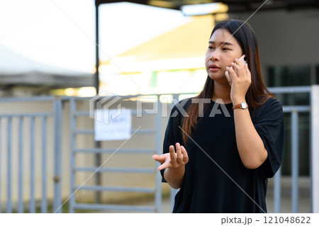 Young asian woman talking on mobile phone in a bright, urban environment 121048622