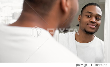 Man care. Skin routine. Morning hygiene. Confident smiling guy with fresh face skin white towel looking in mirror on light free space background. 121049046