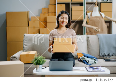Young business owner woman prepare parcel box and standing check online orders for deliver 121049177