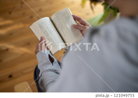 部屋の中で椅子に座って読書をしている中高年女性 121049755