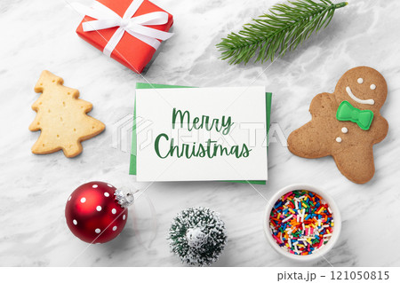 Merry Christmas card and green envelope with gingerbread man, red gift box and christmas decoration on marble table Merry Christmas card and green envelope with gingerbread man, red gift box and christmas decoration on marble table 121050815