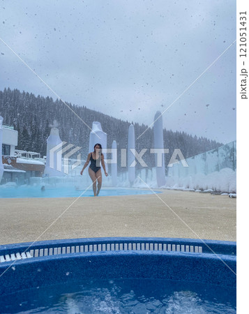 Woman Approaching Hot Tub in Snowy Winter Scene 121051431