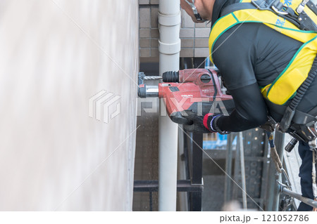 【マンション大規模修繕工事　足場を作る作業員ドリル】 121052786