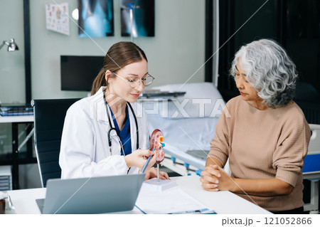 Portrait of female doctor explaining diagnosis to her patient. Doctor Meeting With Patient In Exam Room. A medical practitioner reassuring a patient in hospital 121052866