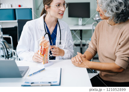 Portrait of female doctor explaining diagnosis to her patient. Doctor Meeting With Patient In Exam Room. A medical practitioner reassuring a patient in hospital 121052899