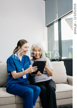 Doctors explain the use of medication to patients. Medical doctor holing senior patient's hands and comforting her on sofa 121052919