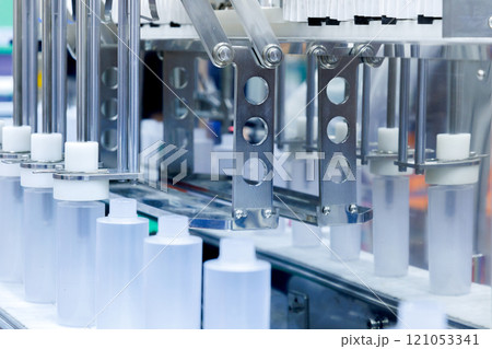 robot arm moving plastic bottle to conveyor belt of auto capping and labeling machine at cosmetic and skin care manufacturing. cosmetic industry and ai technology machinery concept. robot arm moving plastic bottle to conveyor belt of auto capping and labeling machine at cosmetic and skin care manufacturing. cosmetic industry and ai technology machinery concept. 121053341