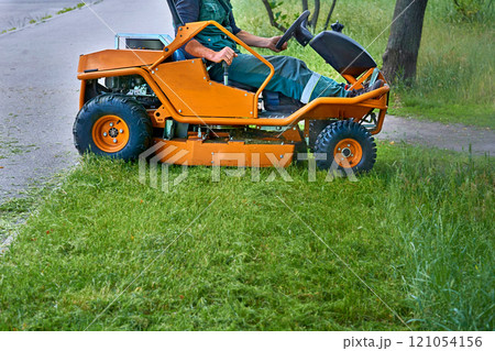 Professional grass cutting on lawns with a lawn mower tractor 121054156