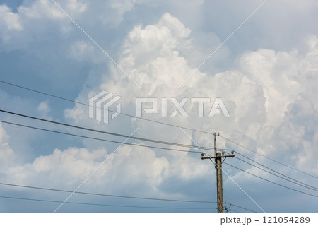 View of utility poles with blue sky and white clouds as a background. 121054289