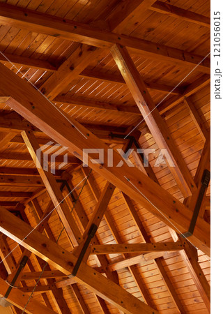 Beautiful sturdy wood architecture of interior roof or ceiling inside a house or building. Wooden beams and natural building material used for interior. Stained wood used for room ceiling feature Beautiful sturdy wood architecture of interior roof or ceiling inside a house or building. Wooden beams and natural building material used for interior. Stained wood used for room ceiling feature 121056015