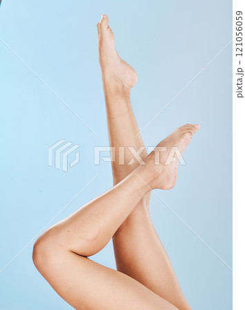 Closeup of unknown woman posing with her soft skin on her legs against a blue studio background. One female only feeling confident while showing her hairless, smooth legs after waxing or epilation 121056059