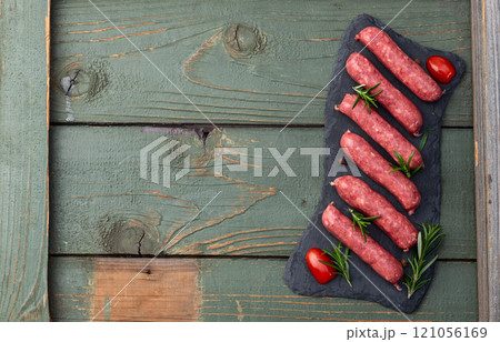 Raw beef sausages with rosemary and tomatoes photography . Top view 121056169