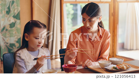 Mom, girl and chopsticks at lunch, home or teaching for food, eating or bonding for love in dining room. People, mother and daughter family house for meal, diet or nutrition with learning in Japan 121056413