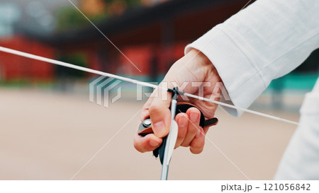 Archery, person and hands with arrow, bow or string for aim, skill or talent in preparation for precision or hunting in city. Japan, closeup or professional archer with weapon for sport or combat Archery, person and hands with arrow, bow or string for aim, skill or talent in preparation for precision or hunting in city. Japan, closeup or professional archer with weapon for sport or combat 121056842