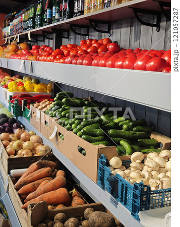 The market is filled with a variety of fresh vegetables, including ripe tomatoes, cucumbers. Inside there is a shop with vegetables and fruits, tomatoes, cucumbers. 121057287