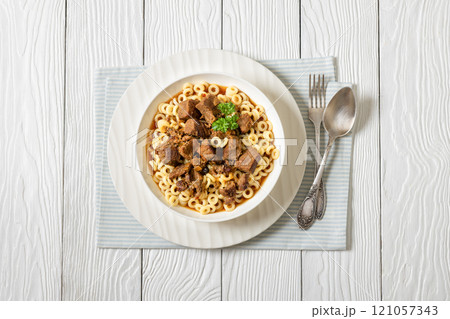 pasta rings topped with braised meat in bowl pasta rings topped with braised meat in bowl 121057343
