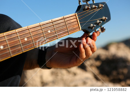 Close-up of a man tuning an acoustic guitar Close-up of a man tuning an acoustic guitar 121058882