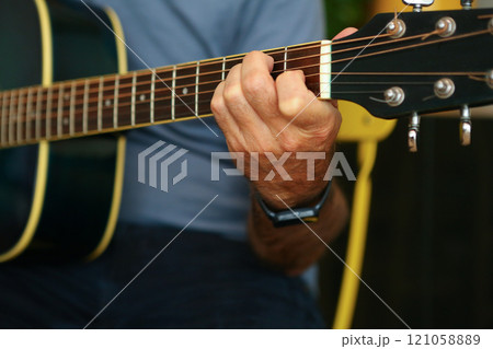 Close-up of a man's hands playing an E chord on acoustic guitar at home chord on acoustic guitar at home 121058889