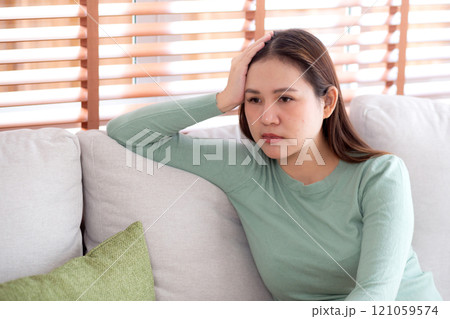 Portrait young asian woman sitting on sofa while frustration with depression in living room at home. 121059574