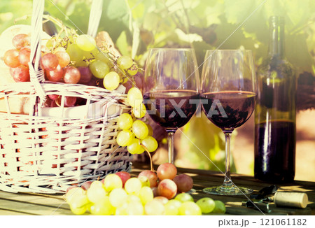 Still life with glass of red wine grapes and picnic basket on table Still life with glass of red wine grapes and picnic basket on table 121061182