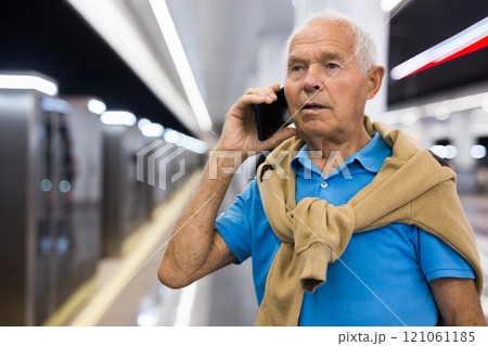 Elderly man talking on phone in subway station Elderly man talking on phone in subway station 121061185