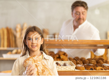 Portrait of little female customer holding bread in his hands in private bakery 121061186