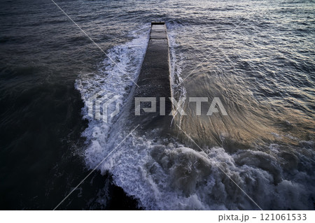 Landscape with a stone pier and raging waves in the sea. 121061533