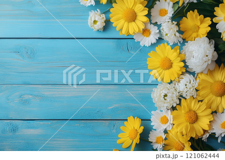 A old wooden plank background with a variety of yellow and white flowers, including daisies on the sides.  121062444