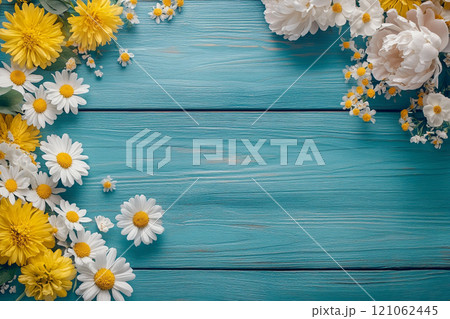 A old wooden plank background with a variety of yellow and white flowers, including daisies on the sides.  121062445