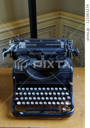 An old fashioned typewriter sits on a wooden table 121063274