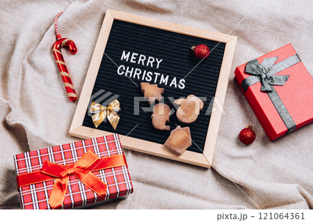 Christmas flatley with a black letter board, with cookies, Christmas tree decorations and gift boxes, on a linen background Christmas flatley with a black letter board, with cookies, Christmas tree decorations and gift boxes, on a linen background 121064361