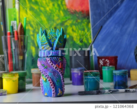 A beautiful ceramic vase vessel in boho marine style after being painted with acrylic and gouache stands to dry on a table in a pottery workshop. High quality photo A beautiful ceramic vase vessel in boho marine style after being painted with acrylic and gouache stands to dry on a table in a pottery workshop. High quality photo 121064368