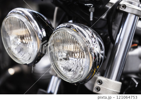 Round front headlights of a shiny black road motorcycle, close up 121064753