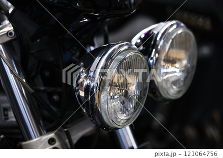 Round front headlights of a shiny black road motorcycle, close-up 121064756