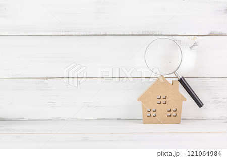 Wooden House with Magnifying Glass on White Wooden Background Representing Real Estate Inspection 121064984