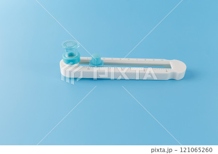 The circle cutter tool with a sliding mechanism with measurements in centimeters, for precise cutting of circles of different sizes. blue background, 121065260