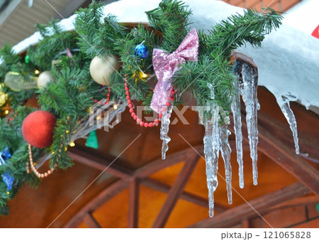 the Christmas garland decorated with balloons on the balcony was covered with icicles and ice in the cold. High quality photo the Christmas garland decorated with balloons on the balcony was covered with icicles and ice in the cold. High quality photo 121065828