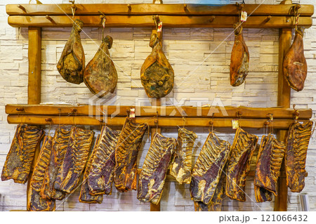 Dried and smoked hams and ribs hang in a traditional butcher shop in a small Croatian town 121066432